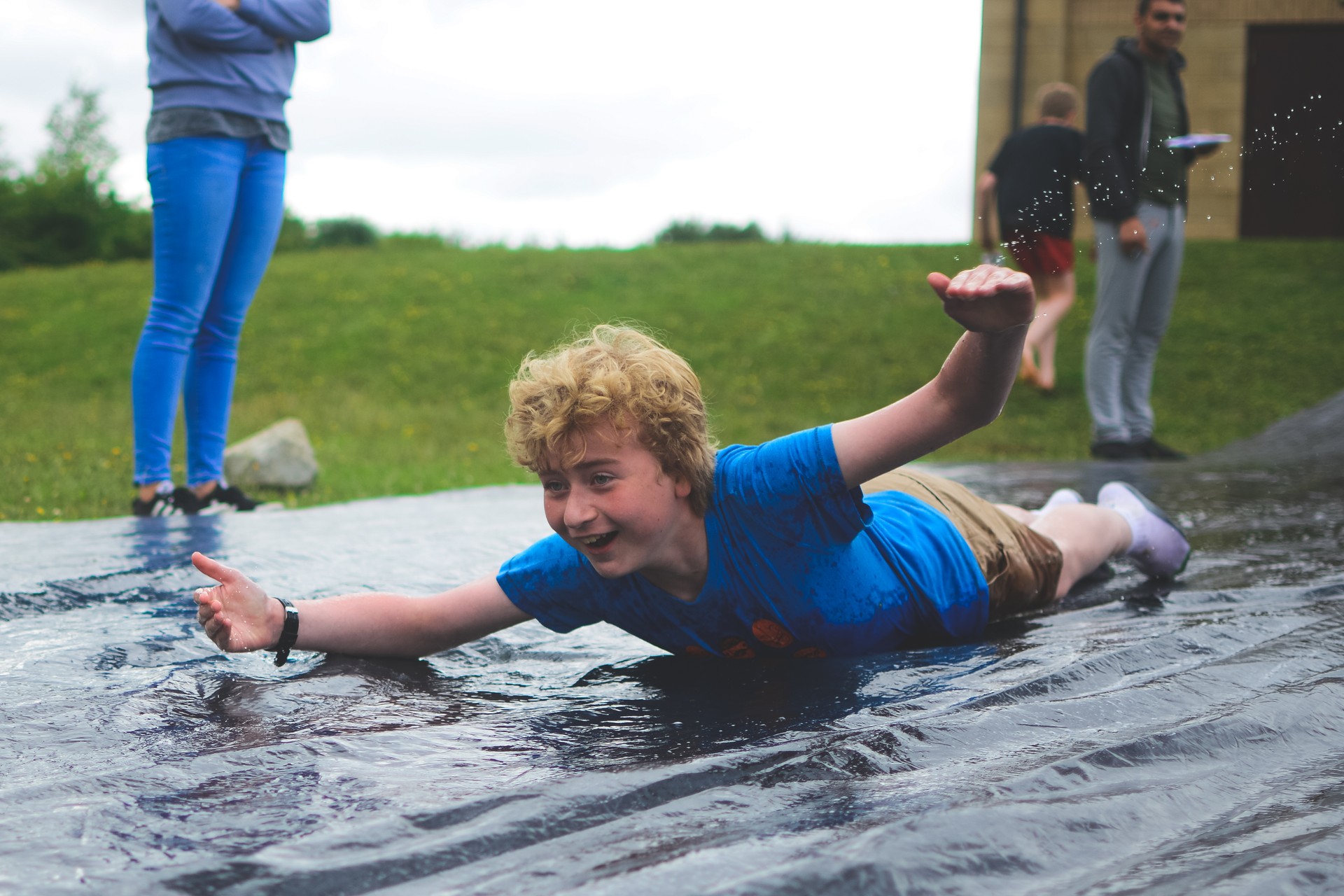 A camper enjoying the water games, sliding down a hill.