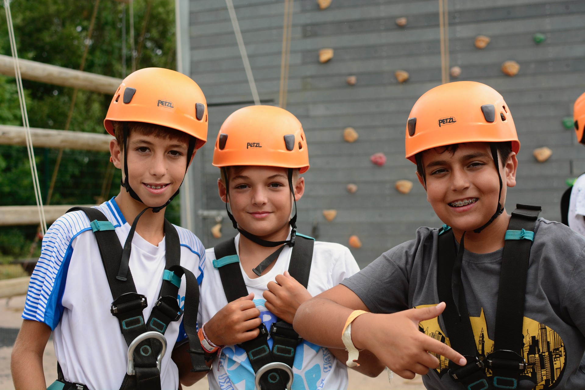 Three campers in front of a climbing wall.